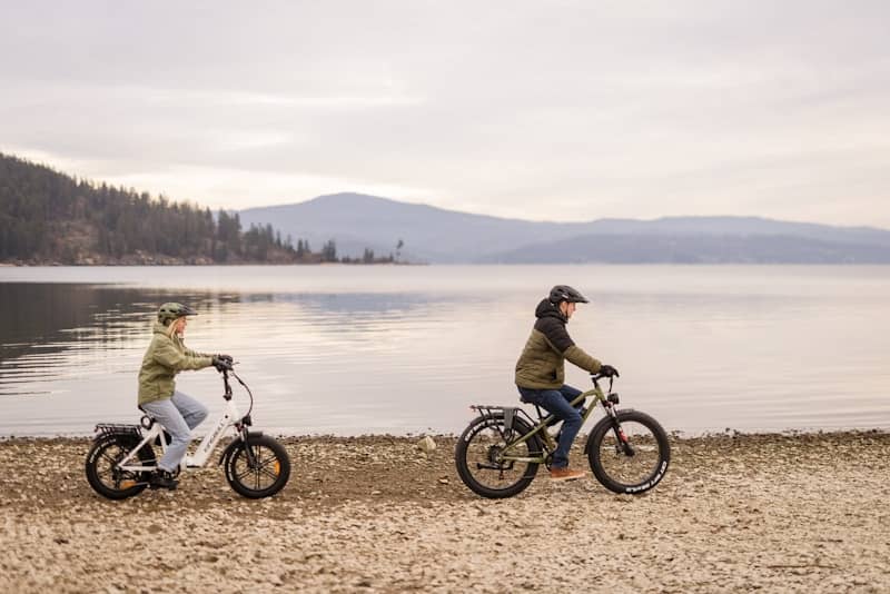 Two people riding bicycles along a lake shore