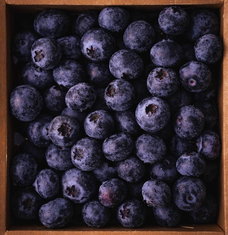 A close-up view of fresh blueberries in a cardboard box.