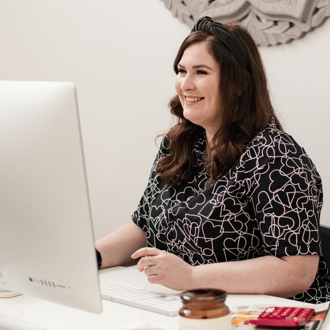 Photo of Emma sitting at the computer, smiling into the webcam