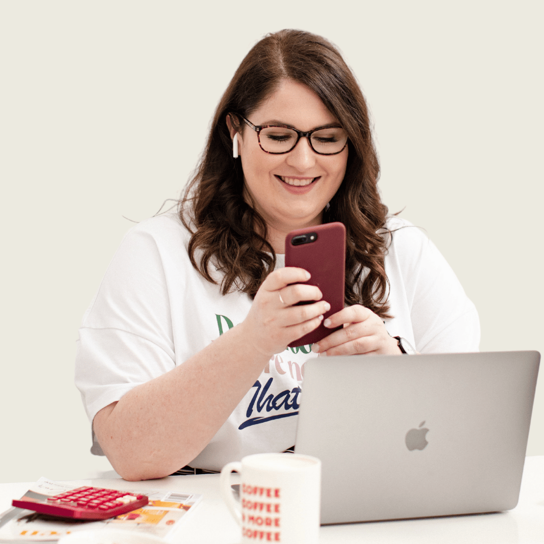 Photo of Emma checking her phone while sitting at her desk