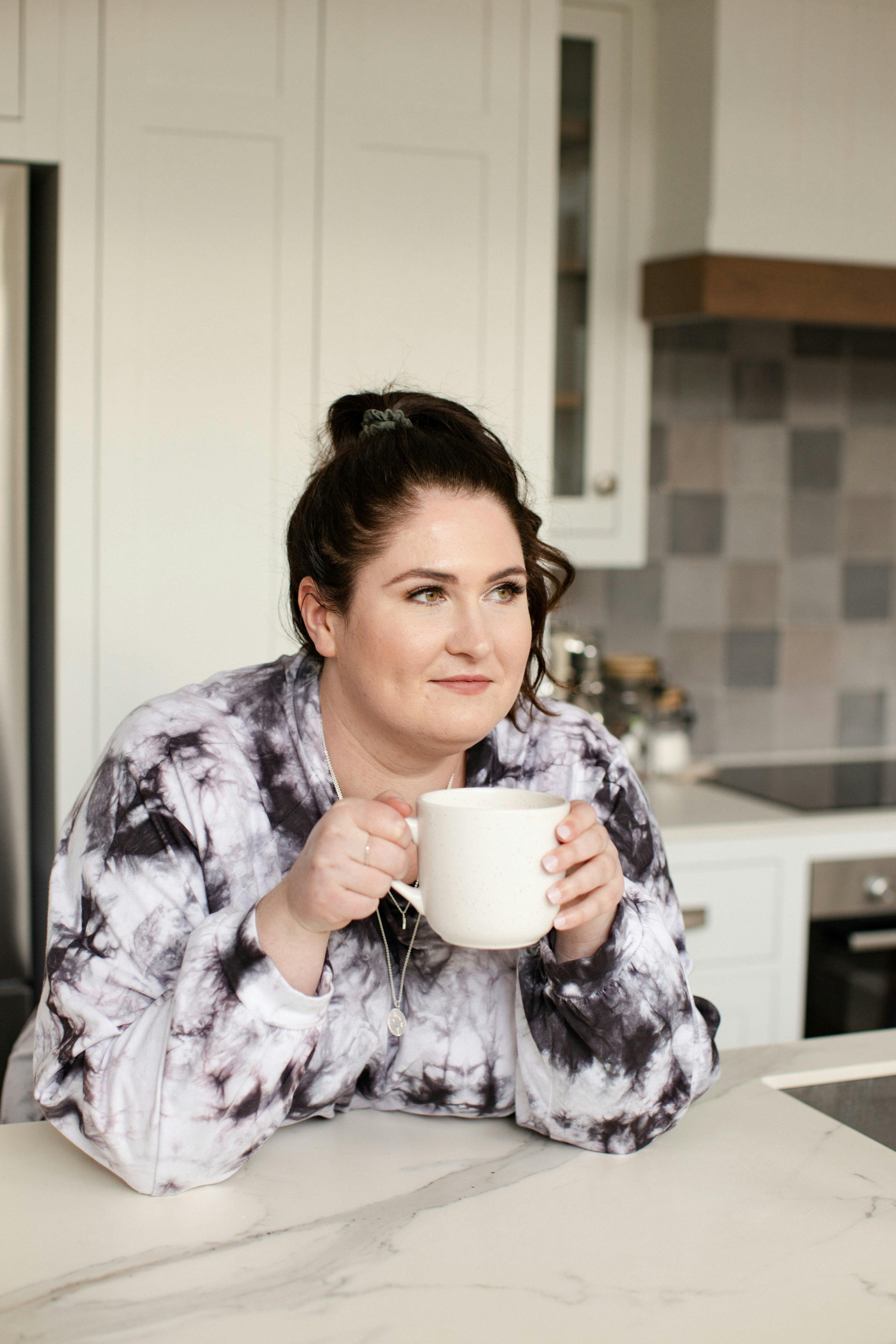 Photo of Emma leaning on a kitchen counter holding a coffee