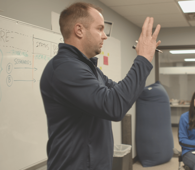 Entrepreneur Nick Berry guiding a small group through leadership and business strategy at a whiteboard.