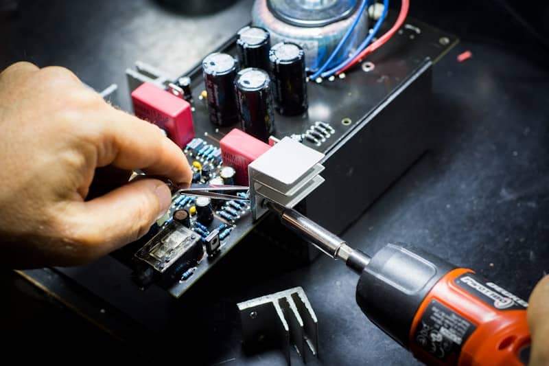 someone screwing something onto a black circuit board which is at least twice the size of the person's hand