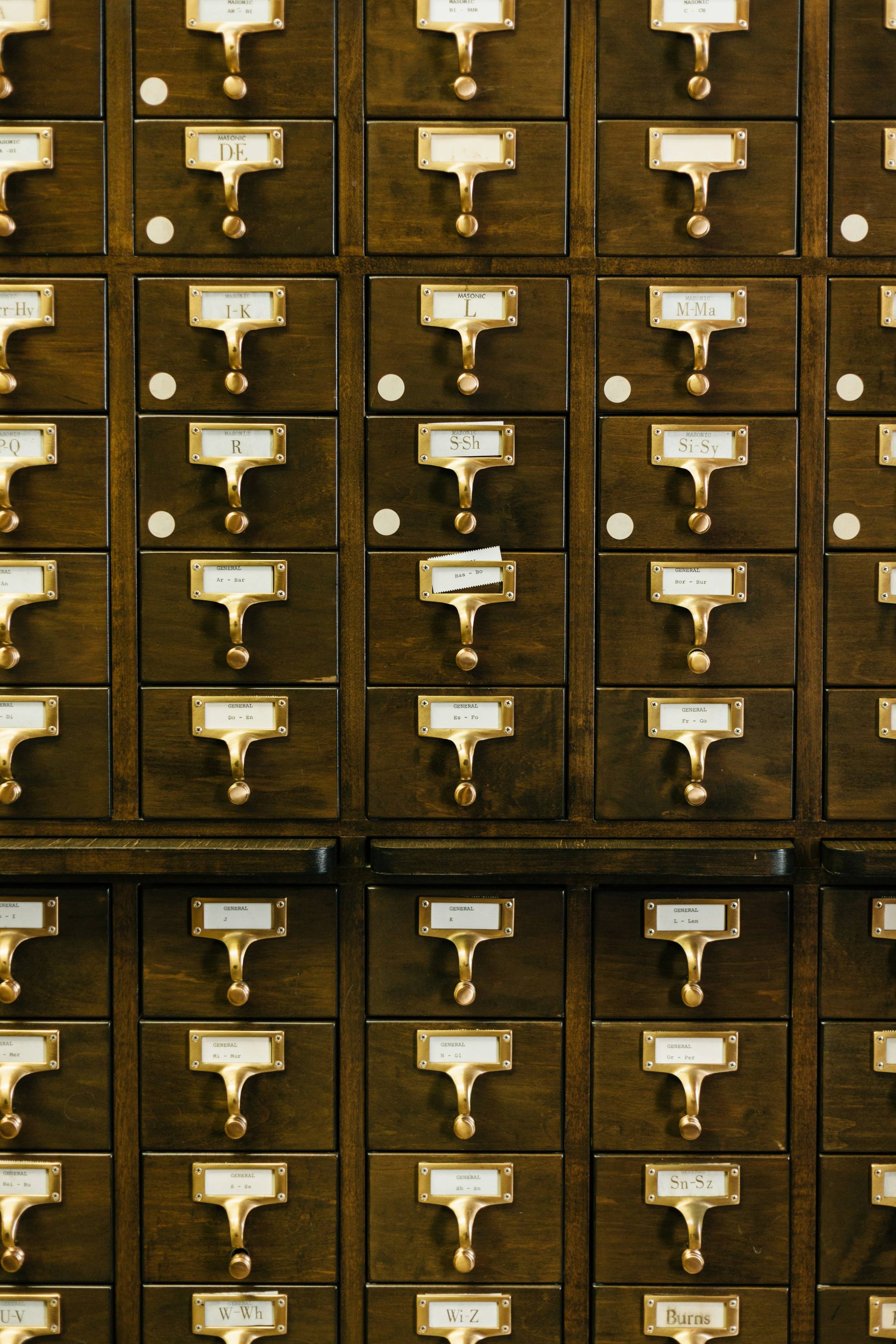 A library card catalog: small wooden drawers with brass handles and paper labels.