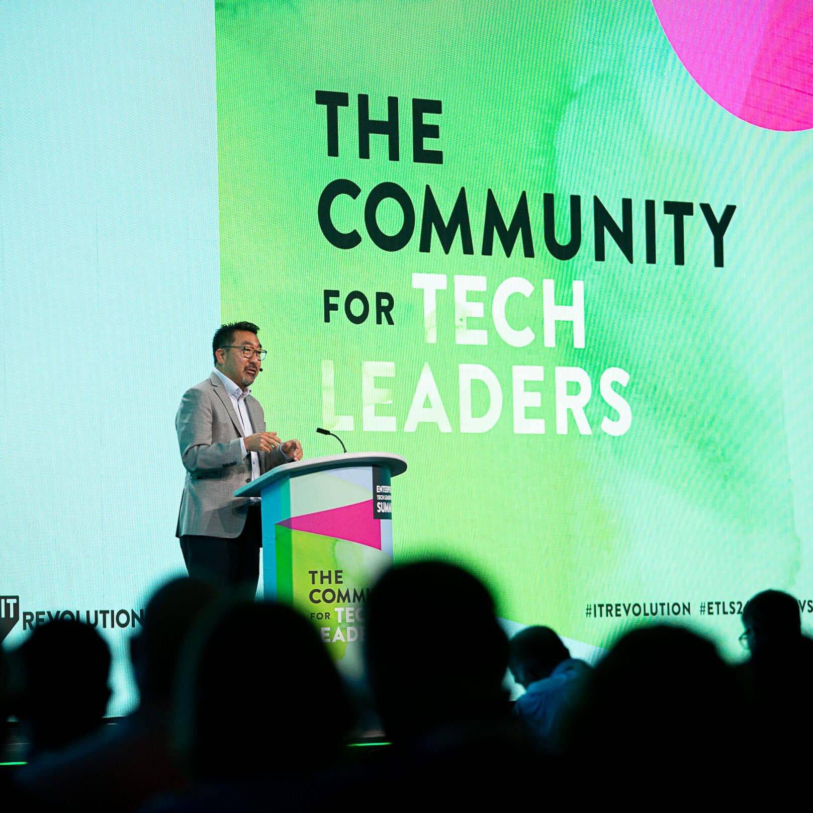 Author Gene Kim on stage at ETLS, in front of a sign that says The Community for Tech Leaders.