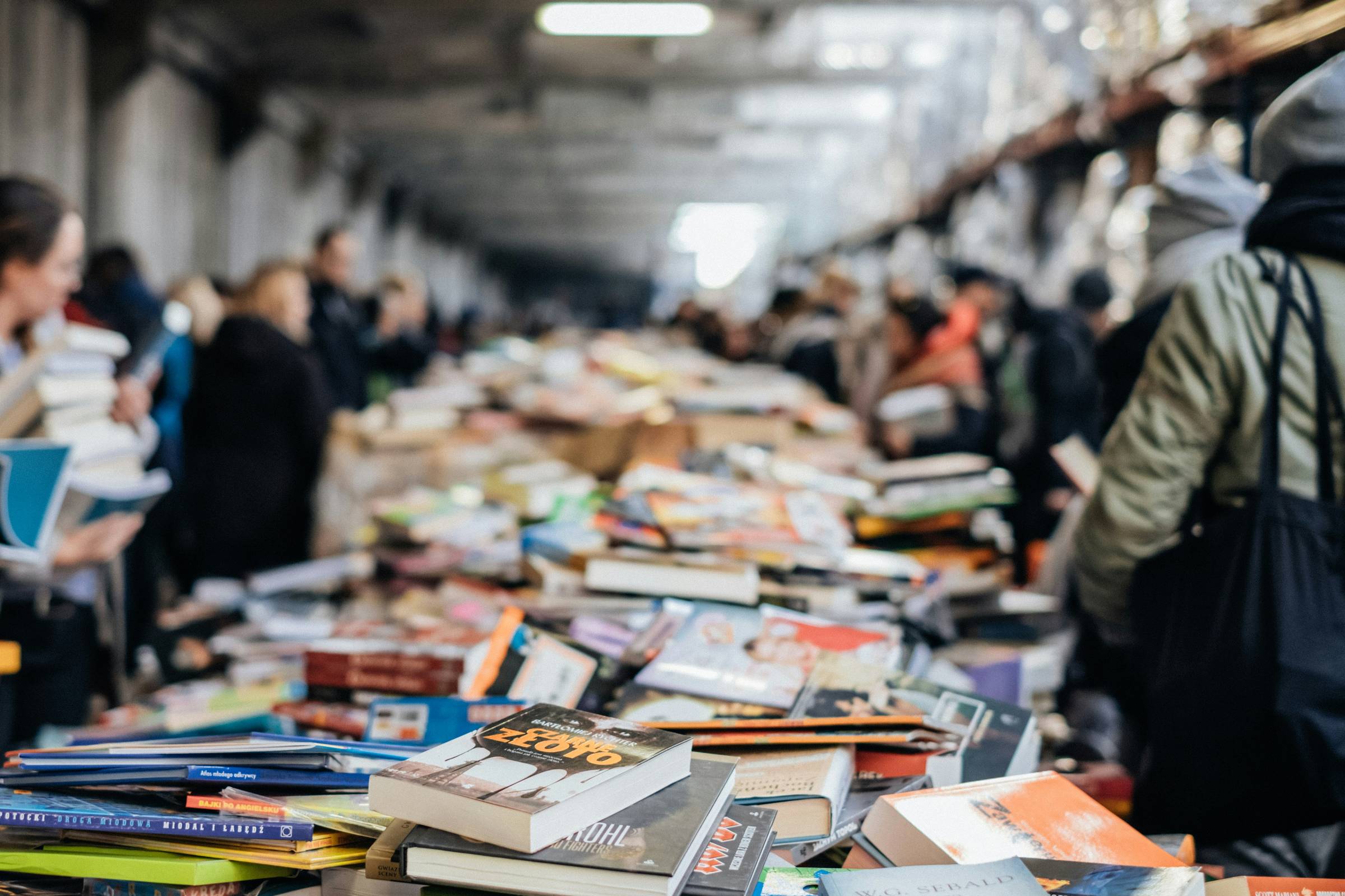 A giant pile of books extending into the distance, with people on either side carrying books.