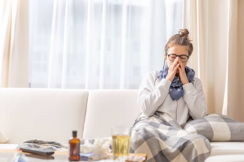 Woman on couch sneezing